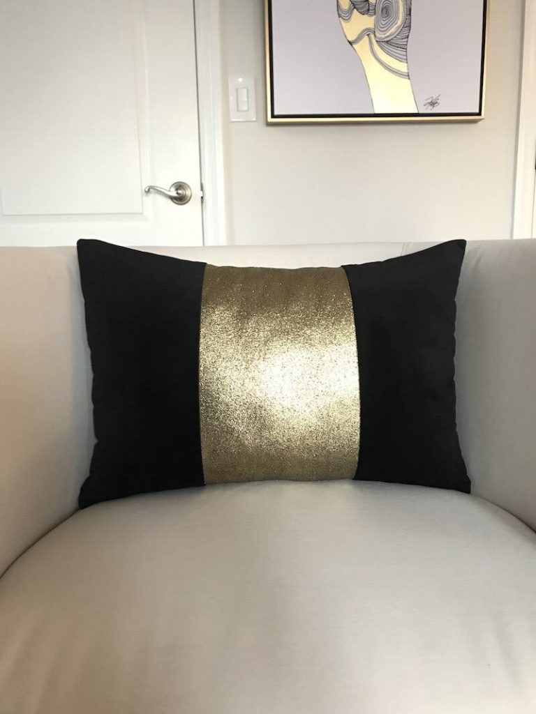 26-black-and-gold-pillow-on-creme-chair